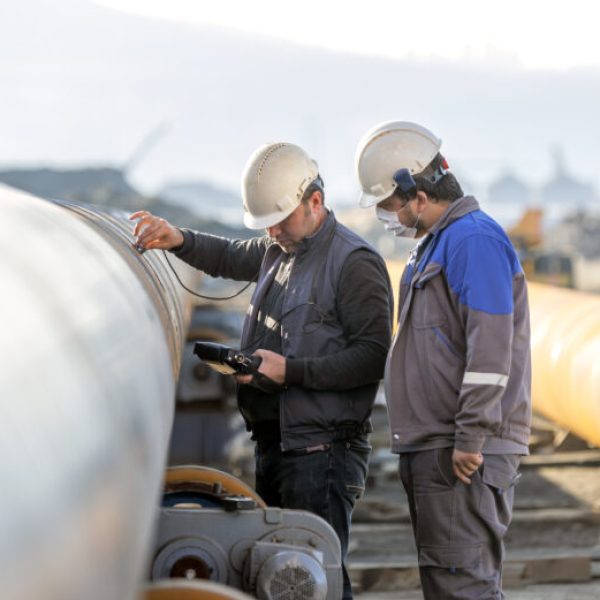 Non-destructive testing technicians are checking welds of pipe with ultrasonic testing (UT) method. Ultrasonic testing is often performed on steel and other metals and alloys.